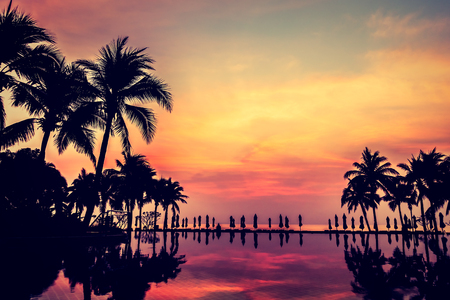 Silhouette palm tree with umbrella and chair around beautiful luxury swimming pool in hotel resort at Sunset time - Vintage Filter and Boost up Color Processingのeditorial素材