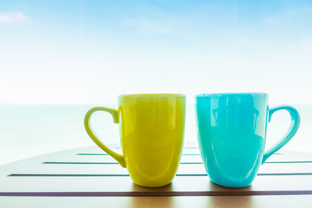 Colorful coffee cup on table with sea background - Boost up color Processingの写真素材