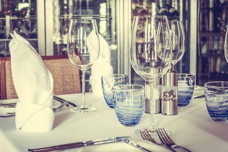 Selective focus point on wine glass with table setting for dinning in hotel restaurant - Vintage...