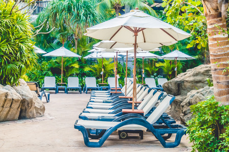 Umbrella and chair around luxury swimming pool landscape with palm tree in hotel resort - Boost up color Processingの写真素材