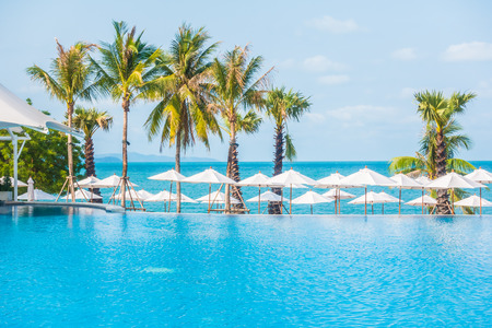 Umbrella and empty chair around swimming pool in hotel resort - Boost up color Processingの写真素材