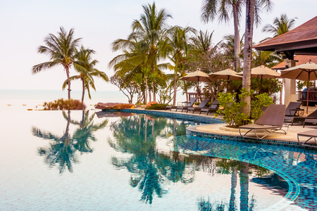 Beautiful luxury swimming pool with palm tree and sea background in hotel pool resort - Vintage Filter and Boost up color Processingのeditorial素材