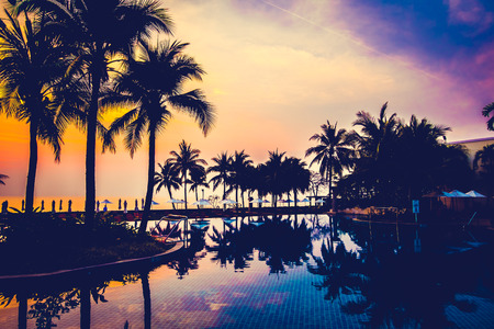 Silhouette palm tree with umbrella and chair around beautiful luxury swimming pool in hotel resort at Sunset time - Vintage Filter and Boost up Color Processingのeditorial素材