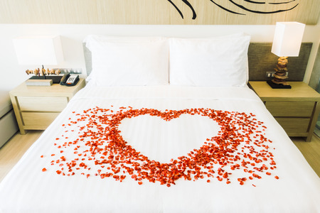 White pillow and Red rose flower on bed decoration in bedroom interior - Vintage Light Filterの写真素材