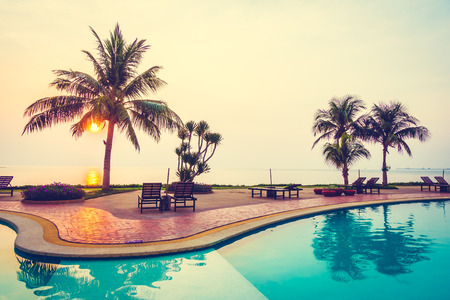 Beautiful Sunrise with silhouette coconut palm tree and chair pool around swimming pool in beautiful luxury hotel resort - Vintage Filterのeditorial素材