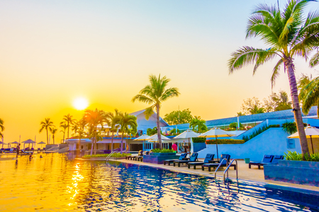 Beautiful Silhouette palm tree with umbrella and chair around luxury swimming pool in hotel resort at sunset time - Vintage Filter and Color boost Up Processingのeditorial素材