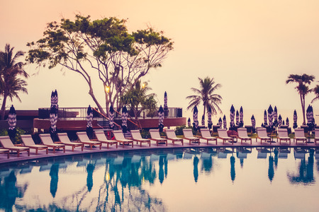 Beautiful luxury outdoor swimming pool in hotel resort with silhouette umbrella and chair and...