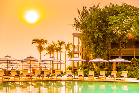 Beautiful luxury outdoor swimming pool in hotel resort with silhouette umbrella and chair and coconut palm tree - Vintage Filter and Boost up color Processingのeditorial素材