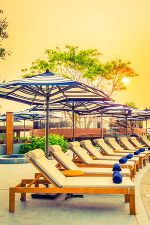 Beautiful luxury outdoor swimming pool in hotel resort with silhouette umbrella and chair and coconut palm tree - Vintage Filter and Boost up color Processingの写真素材