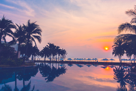 Silhouette palm tree with umbrella and chair around beautiful luxury swimming pool in hotel resort at Sunset time - Vintage Filter and Boost up Color Processingのeditorial素材