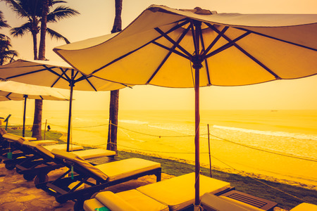 Beautiful Silhouette luxury umbrella and chair around swimming pool in hotel pool resort with coconut palm tree at sunrise times - Vintage Filter and Boost up color Processingの写真素材