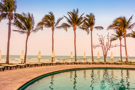 Beautiful luxury umbrella and chair around swimming pool in hotel pool resort with coconut palm tree at sunset times - Vintage Filter and Boost up color Processingのeditorial素材