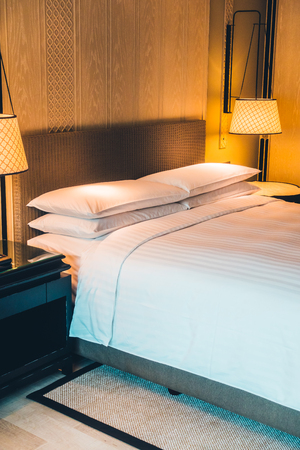 Beautiful luxury white pillow on bed and light lamp on wall decoration in bedroom interior - Vintage Light Filterの写真素材