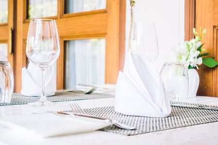 Selective focus point on table setting with wine glass , fork , knife , flower vase and other...