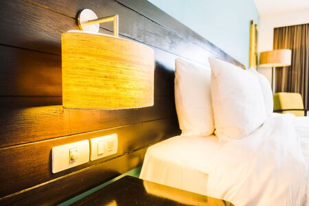 White pillow on bed and light lamp on wall decoration in bedroom interior - Vintage Light Filterの写真素材