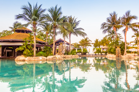 Umbrella and chair around luxury swimming pool landscape with palm tree in hotel resort - Vintage Filter and Boost up color Processingのeditorial素材