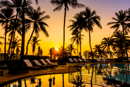 Beautiful luxury outdoor umbrella and chair around swimming pool with silhouette coconut palm tree in hotel resort - Vintage Filterのeditorial素材