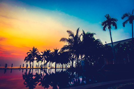 Silhouette palm tree with umbrella and chair around beautiful luxury swimming pool in hotel resort at Sunset time - Vintage Filter and Boost up Color Processingのeditorial素材