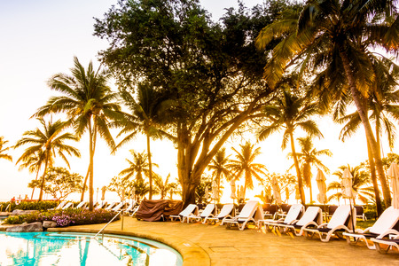 Beautiful luxury outdoor umbrella and chair around swimming pool with silhouette coconut palm tree in hotel resort - Vintage Filterのeditorial素材