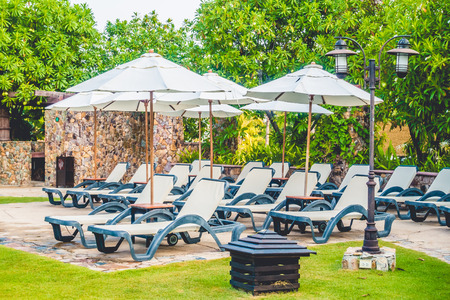 Umbrella and chair around luxury swimming pool landscape with palm tree in hotel resort - Boost up color Processingのeditorial素材