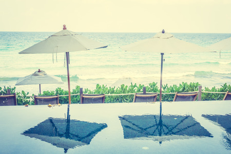 Beautiful luxury Umbrella pool and chair around swimming pool neary beach and sea in hotel resort - Vintage Filterのeditorial素材