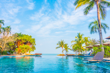 Beautiful luxury swimming pool with palm tree and sea background in hotel pool resort - Boost up color Processingのeditorial素材