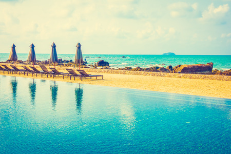 Beautiful luxury umbrella and chair around outdoor swimming pool in hotel resort neary sea and beach...