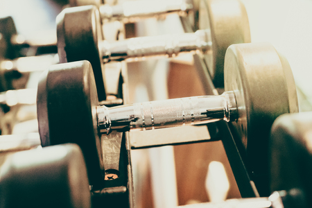 Selective focus point on Dumbbell in fitness and gym room interior - Vintage filter effectの写真素材