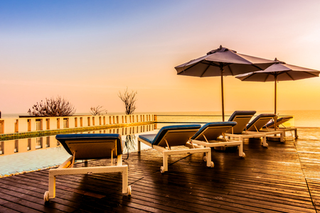 Beautiful luxury swimming pool in hotel resort with silhouette umbrella and chair around pool with sunset and twilight times - Vintage Filter and Boost up color Processingの写真素材