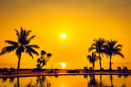 Beautiful Sunrise with silhouette coconut palm tree and chair pool around swimming pool in beautiful luxury hotel resort - Vintage Filterの写真素材