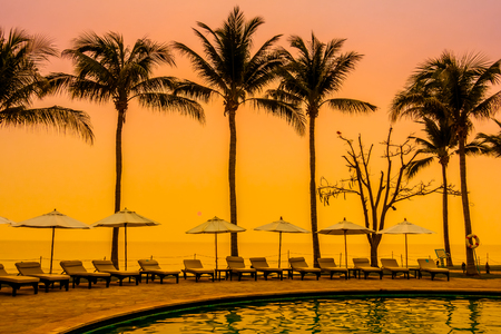 Beautiful Silhouette luxury umbrella and chair around swimming pool in hotel pool resort with coconut palm tree at sunrise times - Vintage Filter and Boost up color Processingのeditorial素材
