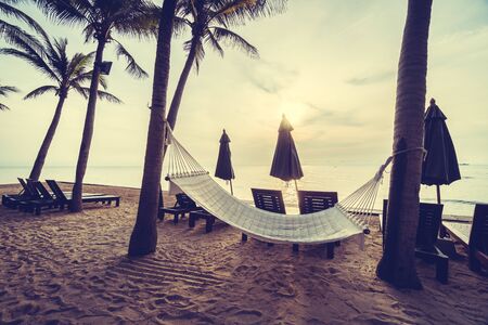 Empty hammock on the beach and sea with coconut palm tree at sunrise time - Vintage Filterの写真素材