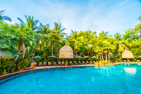 Umbrella and chair around outdoor swimming pool in hotel resort - Holiday vacation background concept - Boost up color Processingのeditorial素材
