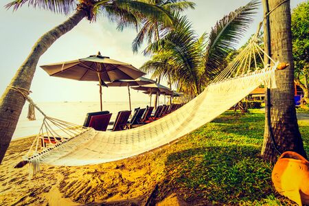 Empty hammock on the beach and sea with coconut palm tree at sunrise time - Vintage Filterの写真素材