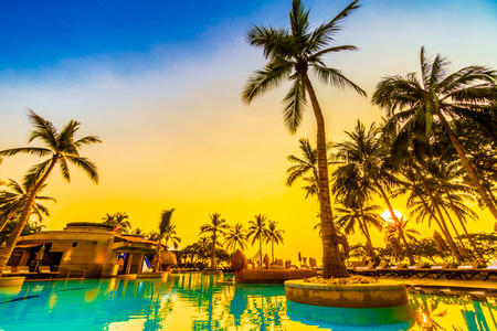 Beautiful luxury umbrella and chair and coconut palm tree around outdoor swimming pool in hotel resort at sunrise time - Vintage filter and boost up color Processingのeditorial素材