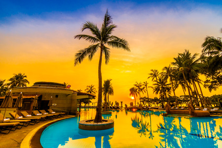 Beautiful luxury umbrella and chair and coconut palm tree around outdoor swimming pool in hotel resort at sunrise time - Vintage filter and boost up color Processingのeditorial素材