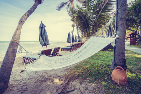 Empty hammock on the tropical beach and sea with umbrella and chair - Vintage Filterの写真素材
