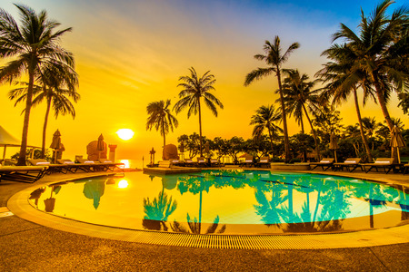 Beautiful luxury umbrella and chair and coconut palm tree around outdoor swimming pool in hotel resort at sunrise time - Vintage filter and boost up color Processingのeditorial素材