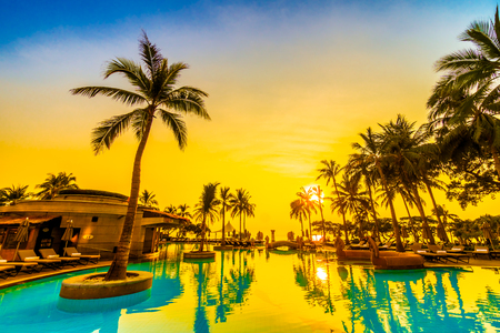Beautiful luxury umbrella and chair and coconut palm tree around outdoor swimming pool in hotel resort at sunrise time - Vintage filter and boost up color Processingのeditorial素材
