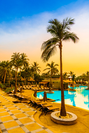 Beautiful luxury umbrella and chair and coconut palm tree around outdoor swimming pool in hotel resort at sunrise time - Vintage filter and boost up color Processingのeditorial素材