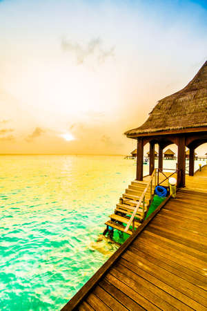 Beautiful tropical Sunset over maldives island with water bungalow in hotel resort - Vintage Filter and Boost up color Processingの写真素材
