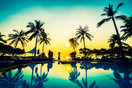 Beautiful luxury umbrella and chair and coconut palm tree around outdoor swimming pool in hotel resort at sunrise time - Vintage filter and boost up color Processingのeditorial素材
