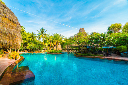 Umbrella and chair around outdoor swimming pool in hotel resort - Holiday vacation background concept - Boost up color Processingのeditorial素材