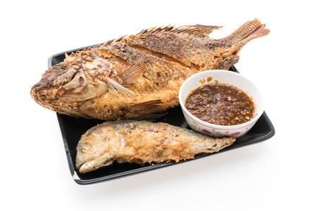 Fried fish meat in black plate with spicy sauce isolated on white backgroundの写真素材