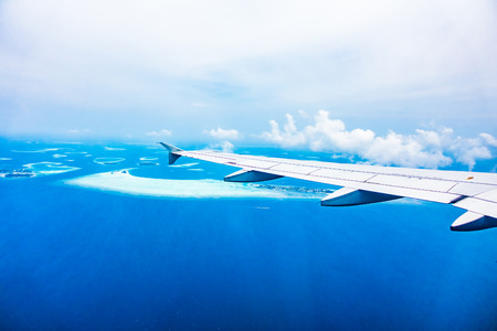 AIrplane wing with beautiful tropical aerial view of maldives island and sea - Boost up color Processingの写真素材