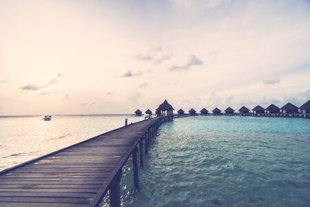 Beautiful tropical Sunset over maldives island with water bungalow in hotel resort - Vintage Filter and Boost up color Processingのeditorial素材