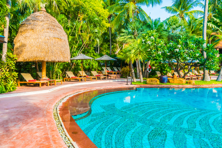 Umbrella and chair around outdoor swimming pool in hotel resort - Holiday vacation background concept - Boost up color Processingのeditorial素材