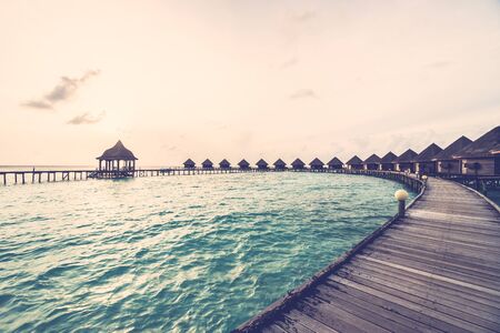 Beautiful tropical Sunset over maldives island with water bungalow in hotel resort - Vintage Filter and Boost up color Processing