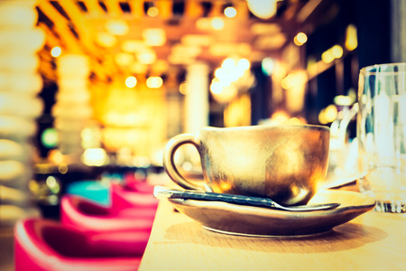 Selective focus point on coffee cup in coffee shop cafe and restaurant interior - Vintage filter and sunflare effectの写真素材