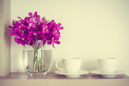 White coffee cup with orchid flower vase decoration interior of room - Vintage Filterの写真素材